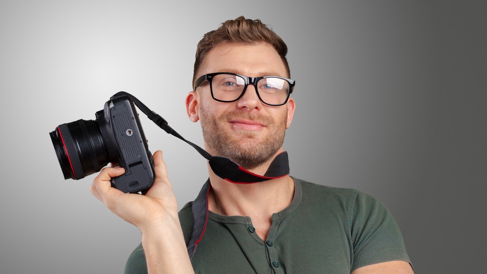 Lächelnder Mann mit Brille hält eine Kamera – professionelle Bewerbungsfotos
