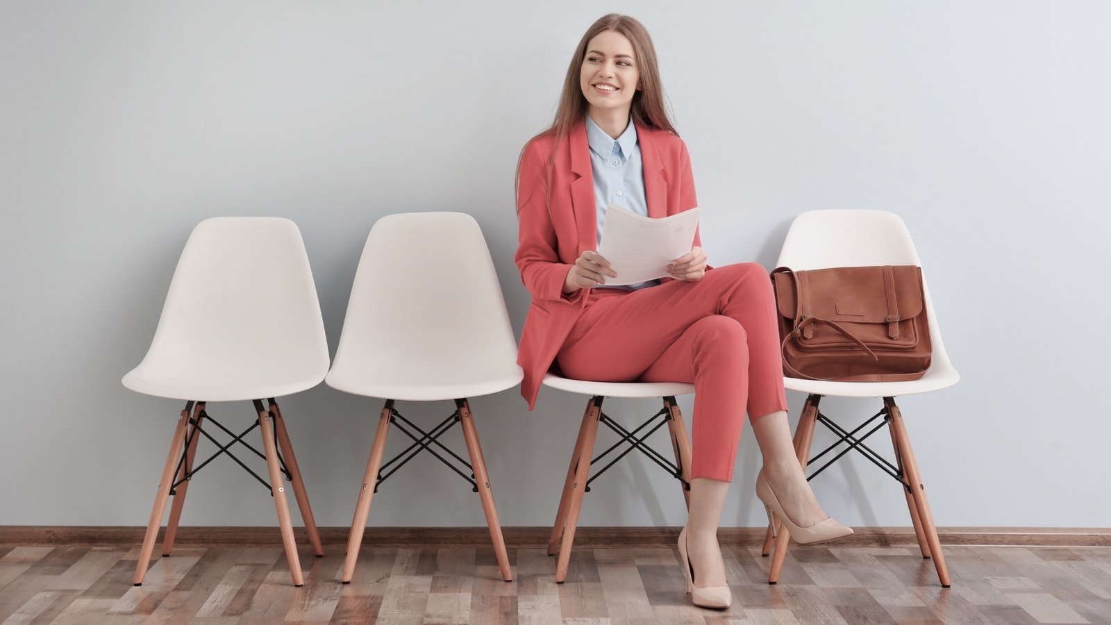 Manchmal trifft eine Spontanbewerbung genau zum richtigen Zeitpunkt am richtigen Ort ein. Bewirbdich.ch hilft gerne dabei. Bewerberin im roten Anzug wartet mit Unterlagen im Wartebereich – Blindbewerbung