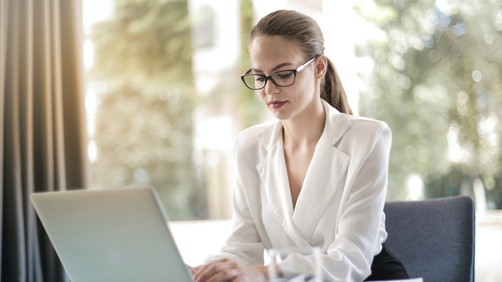 Junge Frau mit Brille arbeitet konzentriert am Laptop – Kundenstimme