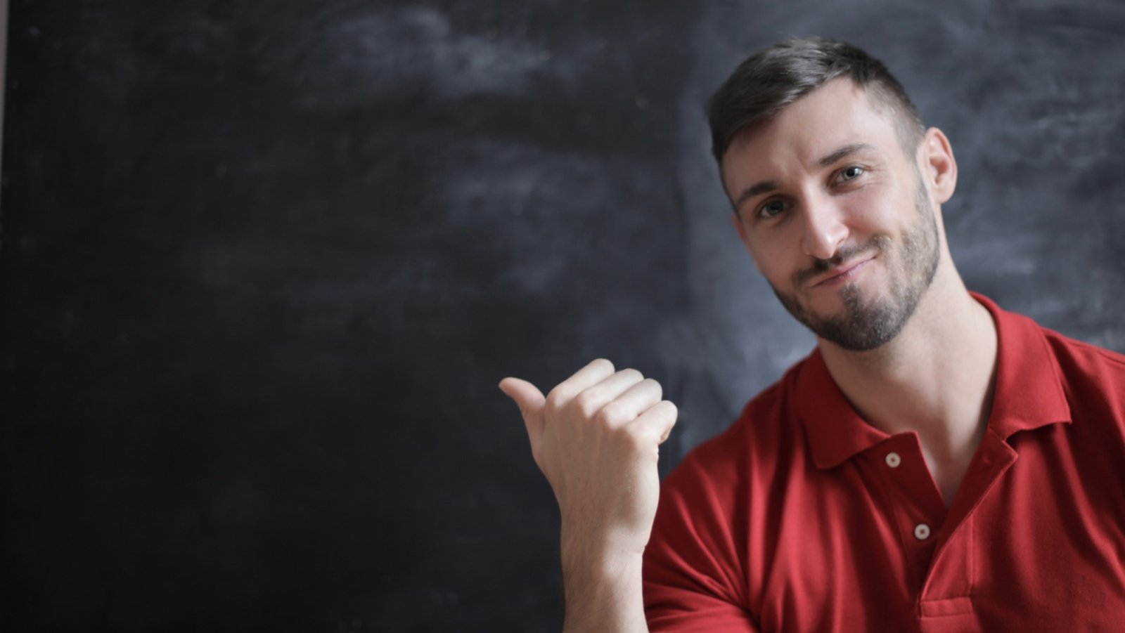 Lächelnder Mann im roten Poloshirt zeigt mit dem Daumen zur Seite – Kundenstimme