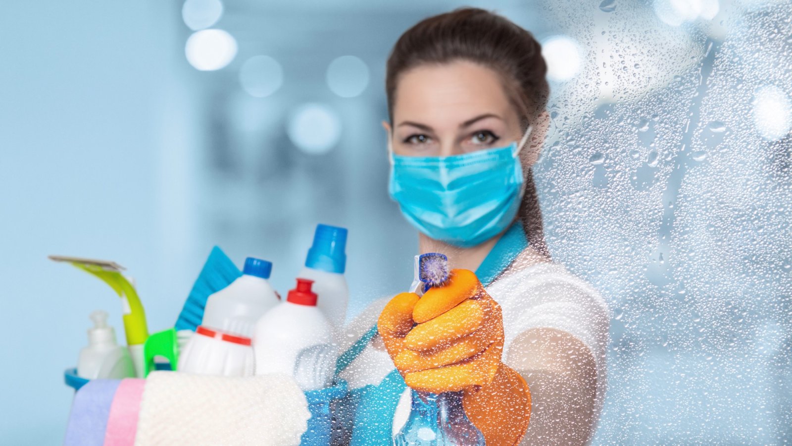 Reinigungskraft mit Maske und Putzmitteln reinigt eine Glasscheibe – Kundenstimme