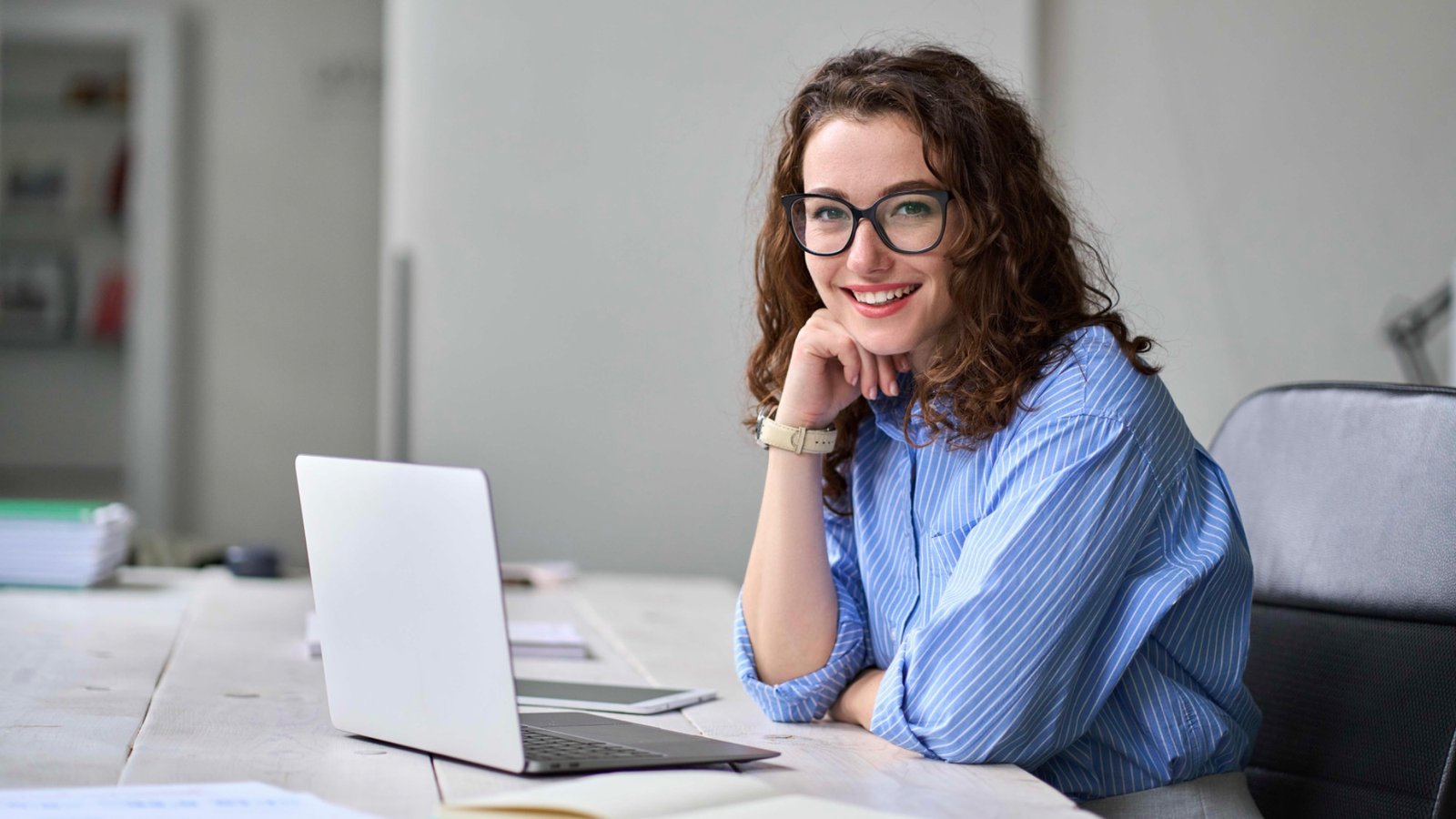 Senden Sie Ihre Infos und Unterlagen direkt an Bewirbdich.ch - meine Rückmeldung erfolgt sofort. Lächelnde junge Frau mit Brille am Laptop – Ablauf und Preise der Bewerbungshilfe