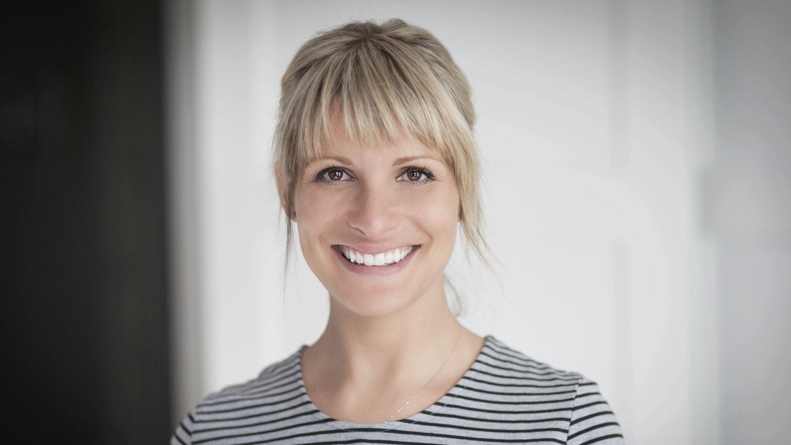Lächelnde blonde Frau im gestreiften Shirt – gutes Bewerbungsfoto