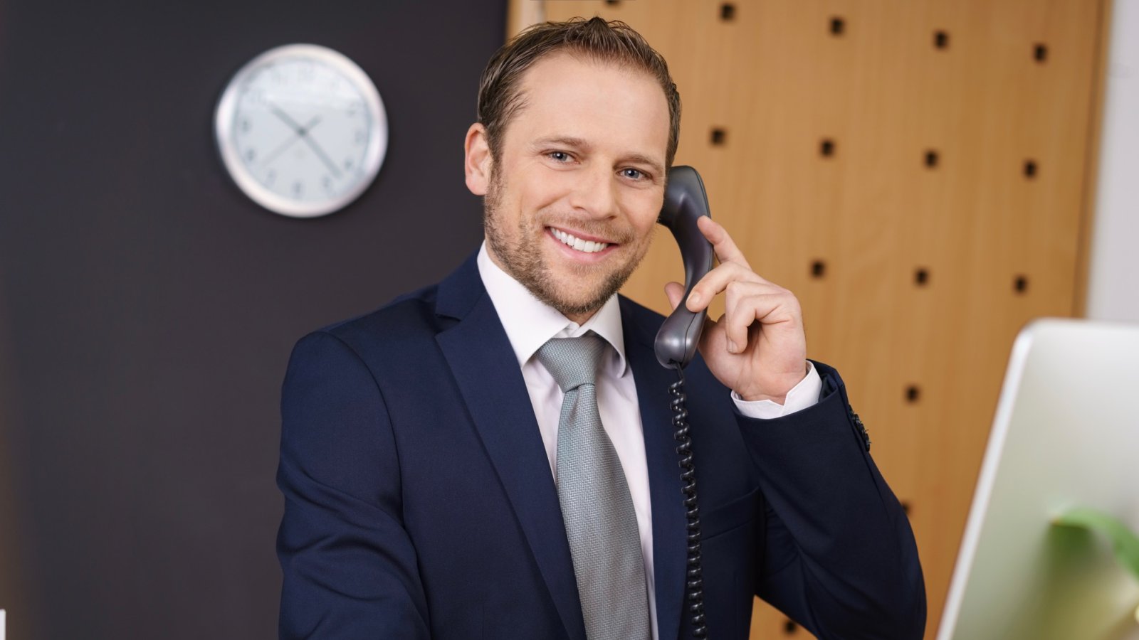 Lächelnder Mann im Anzug telefoniert im Büro – Kundenstimme