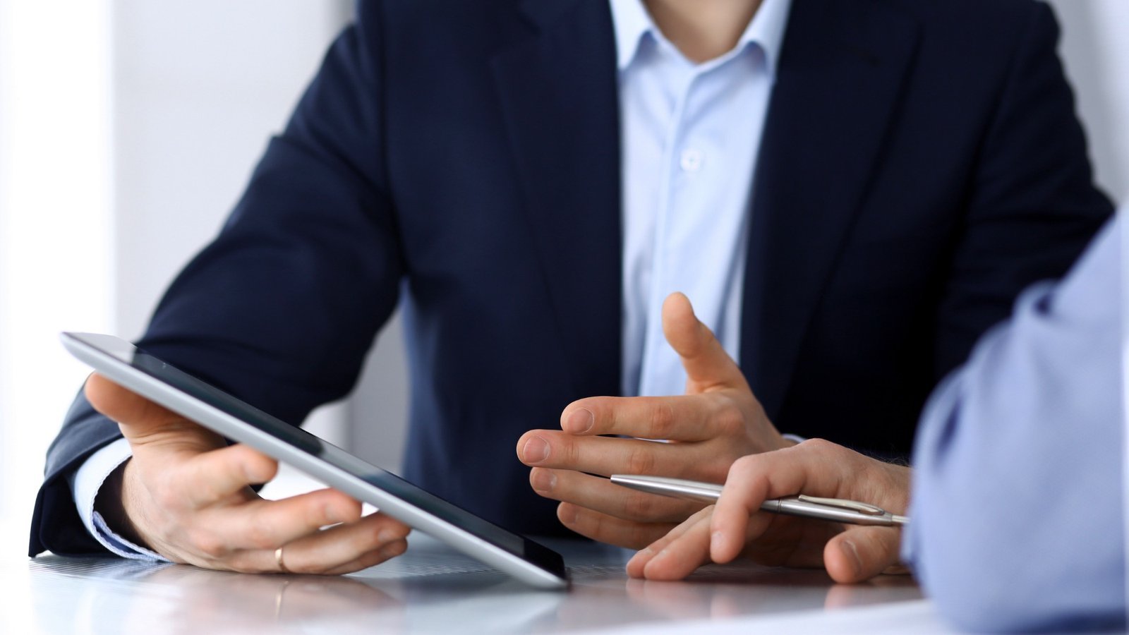 Hände mit Tablet und Stift im Gespräch – clever über den Lohn verhandeln