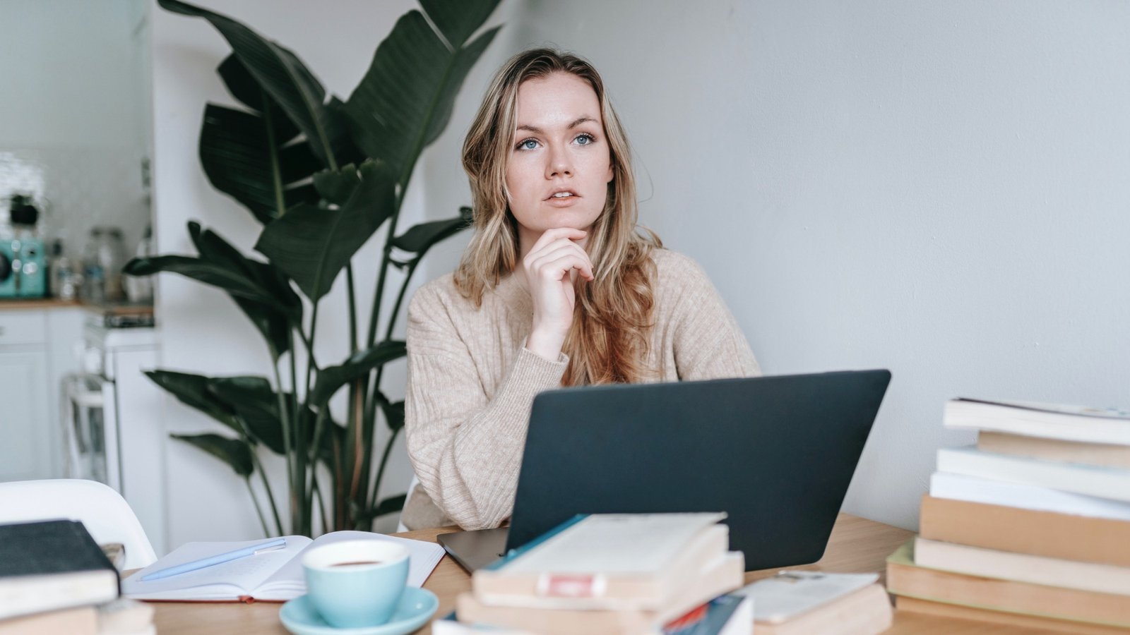 Nachdenkliche Frau am Laptop zwischen Büchern – handeln, wenn die Kündigung droht