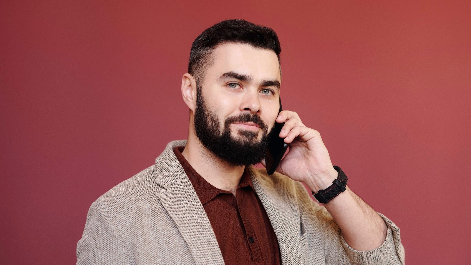 Mann mit Bart im Sakko telefoniert vor roter Wand – Problem Chef
