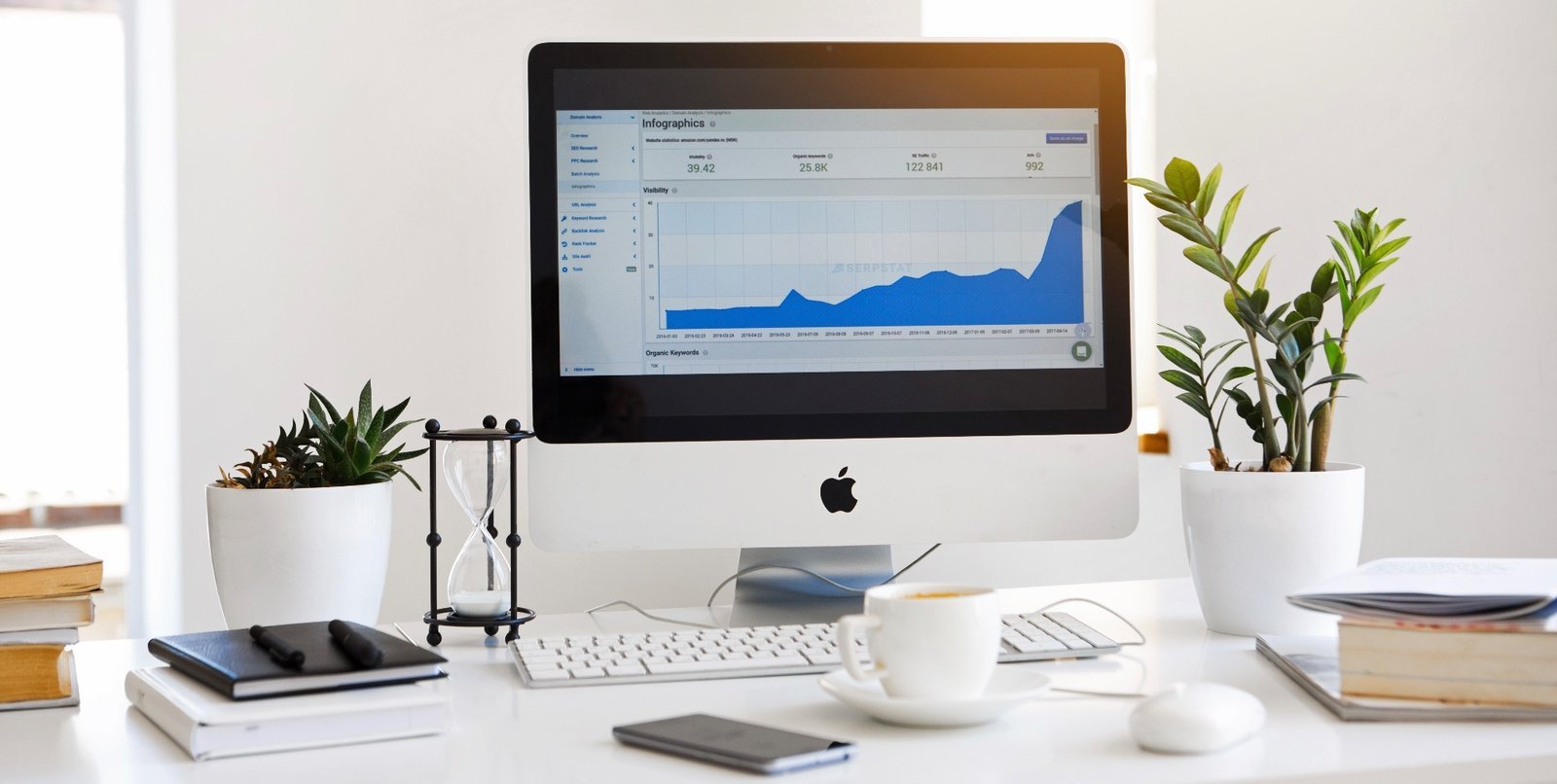 Aufgeräumter Arbeitsplatz mit Computer, Pflanzen und Kaffeetasse – Home Office